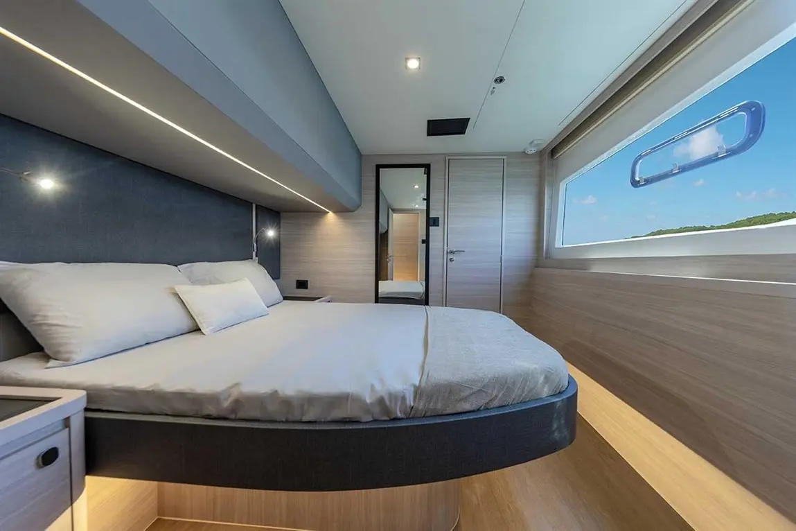 Modern bedroom design featuring a double bed, natural light, sleek furnishings, and a large window with scenic views.