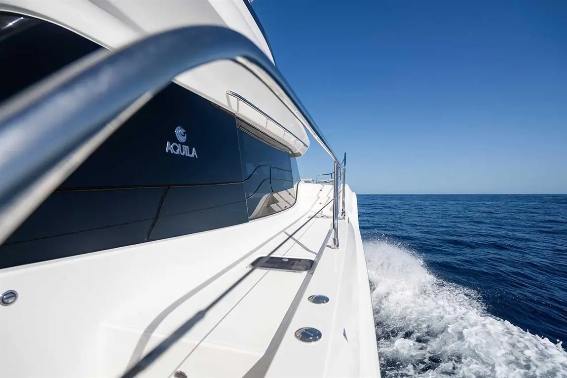 Aquila powerboat slicing through calm blue waters under a clear sky, showcasing sleek lines and elegant design.