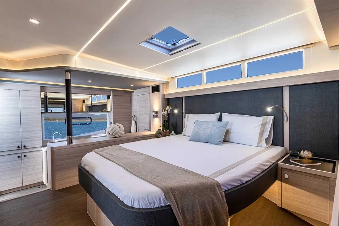 Luxurious yacht cabin featuring a double bed, scenic ocean views through large windows, and modern furnishings.