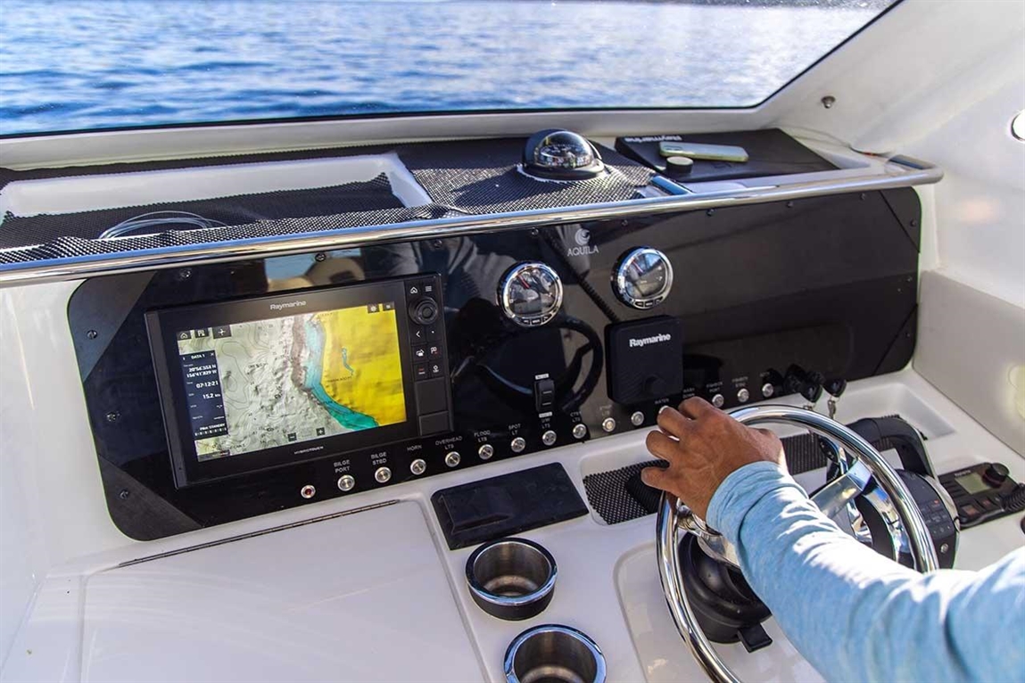 A close-up of a boat's control panel with a map display and a person steering, highlighting navigation and marine technology.