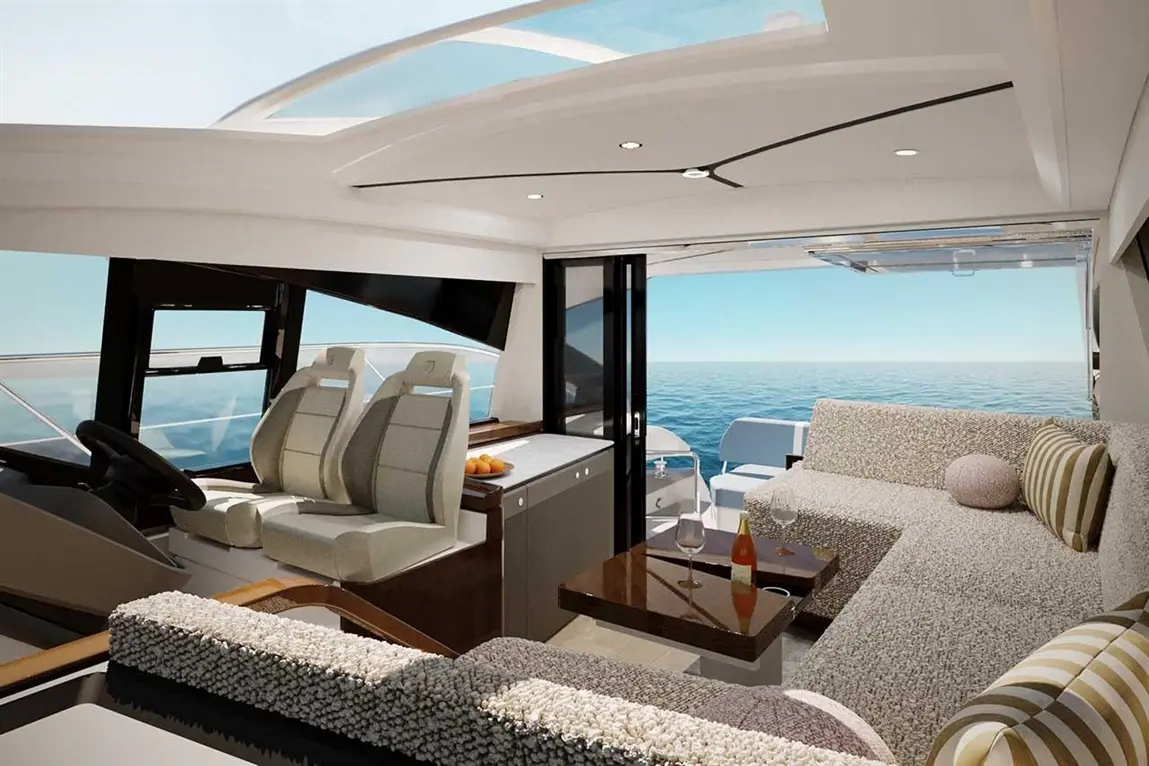Modern yacht interior featuring plush seating, a dining area, and large windows overlooking the ocean, with fruit on the table.