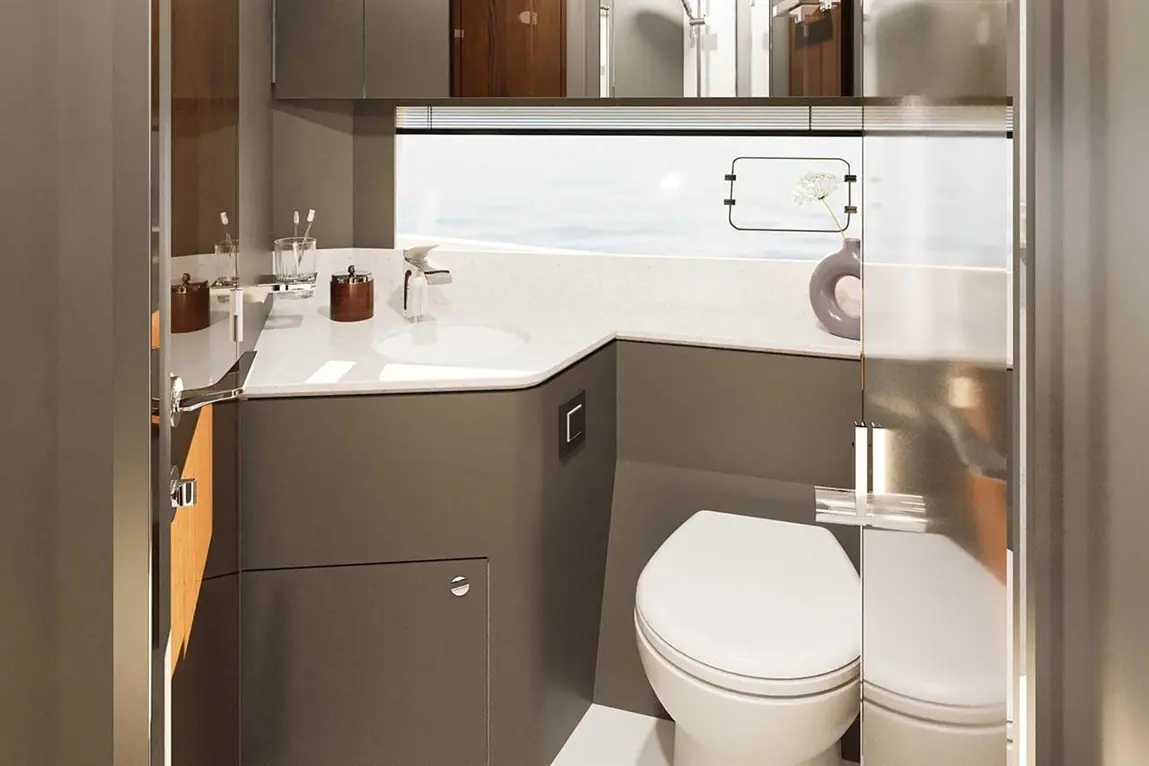 Modern bathroom with a white toilet, sink, and wooden shelves, featuring natural light and a vase with a flower.
