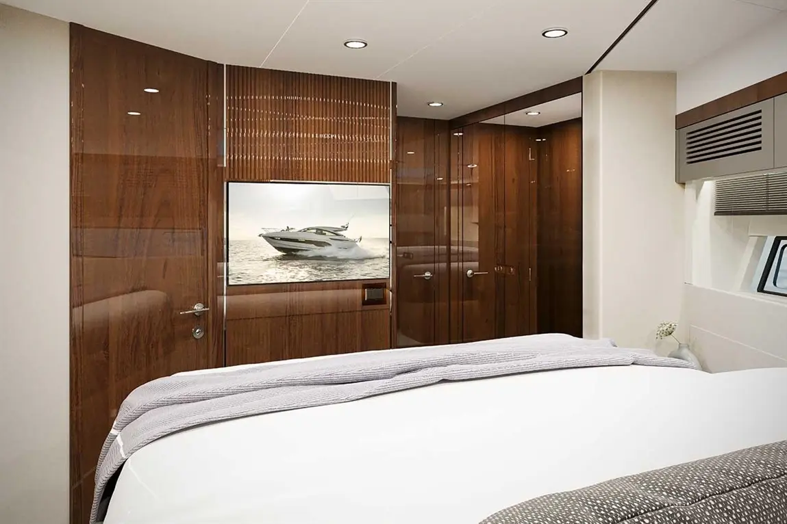 Luxury yacht bedroom featuring a double bed, wooden panels, and a TV showing a yacht on water.