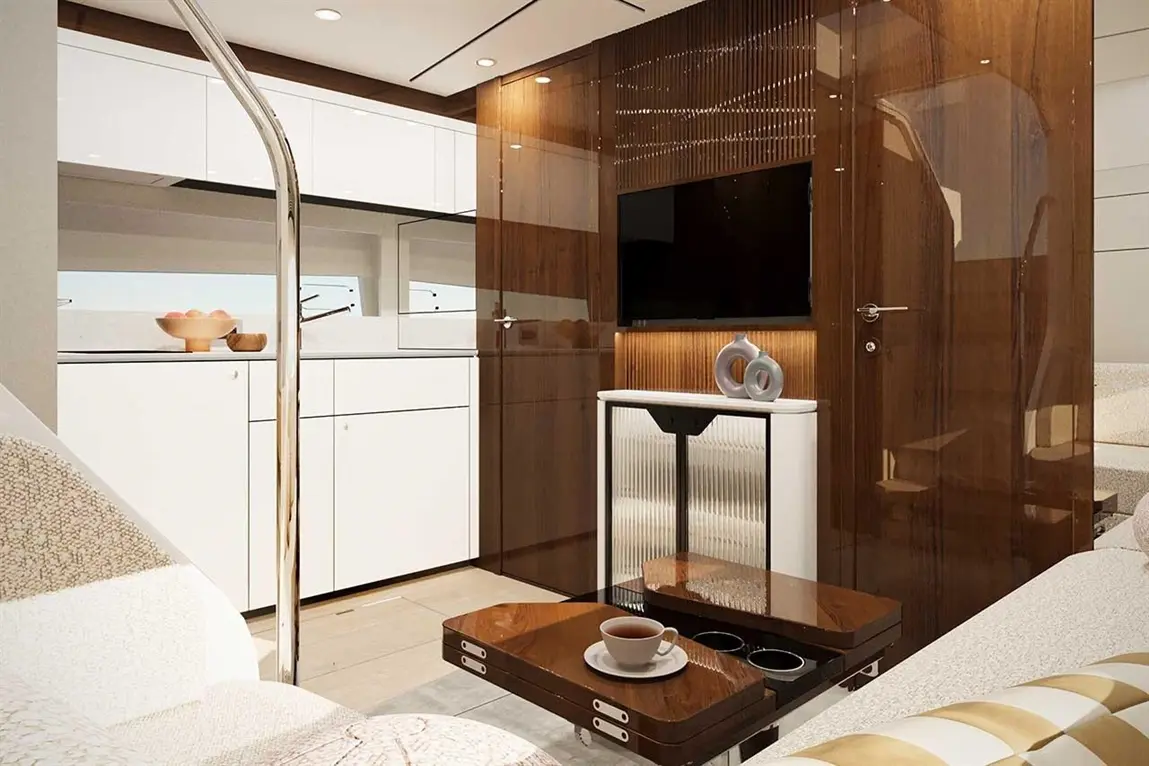 Modern boat interior featuring a kitchen area, brown wooden accents, a TV, and a coffee table with a cup of coffee.