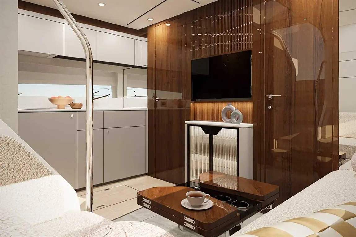 Modern yacht interior featuring wood accents, a TV, coffee table with cup, grey cabinets, and bright lighting.