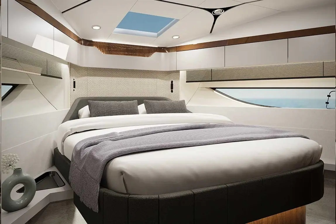 Modern boat interior featuring a double bed with grey linens and cushions, skylight, and stylish decor with ocean views.