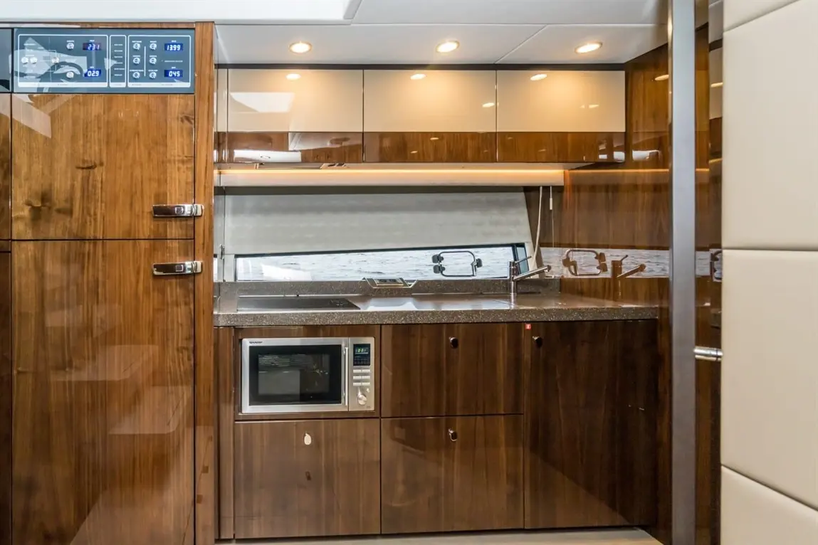 Modern kitchen with wooden cabinetry, countertop, microwave, and a window overlooking the water; sleek and stylish design.
