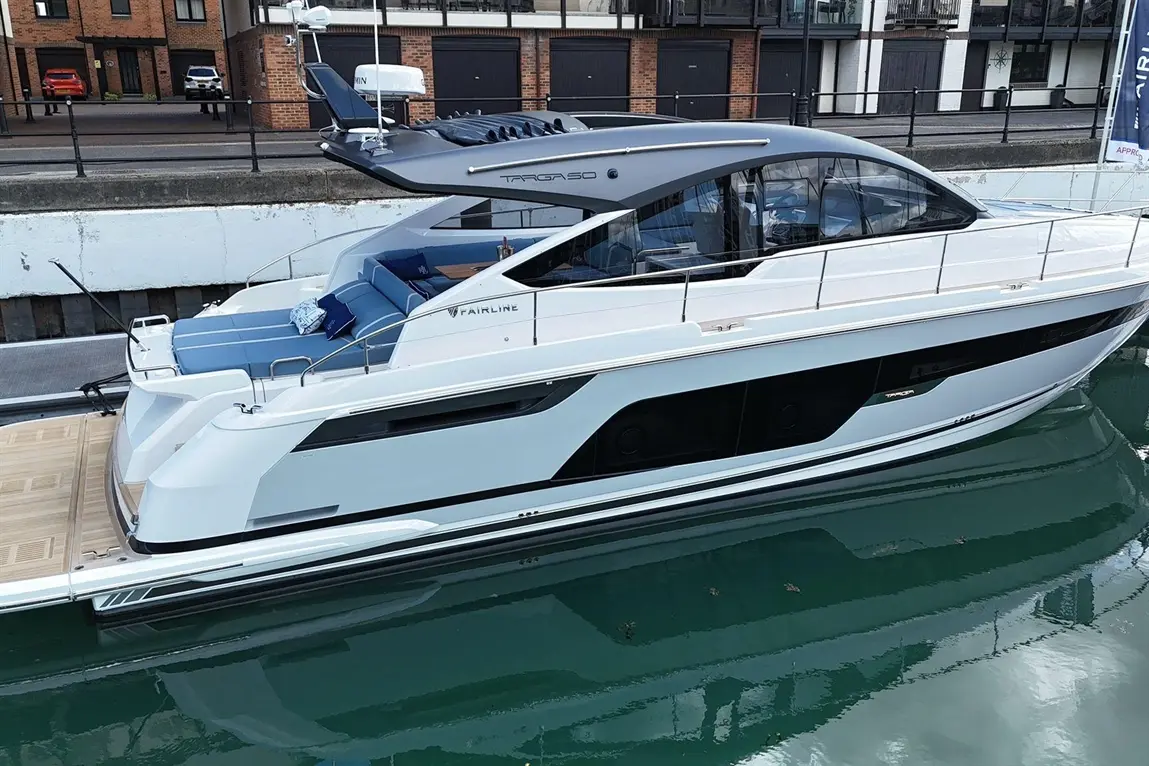 A luxurious Fairline Targa 50 motorboat docked, featuring stylish seating and sleek design, reflected in calm water.