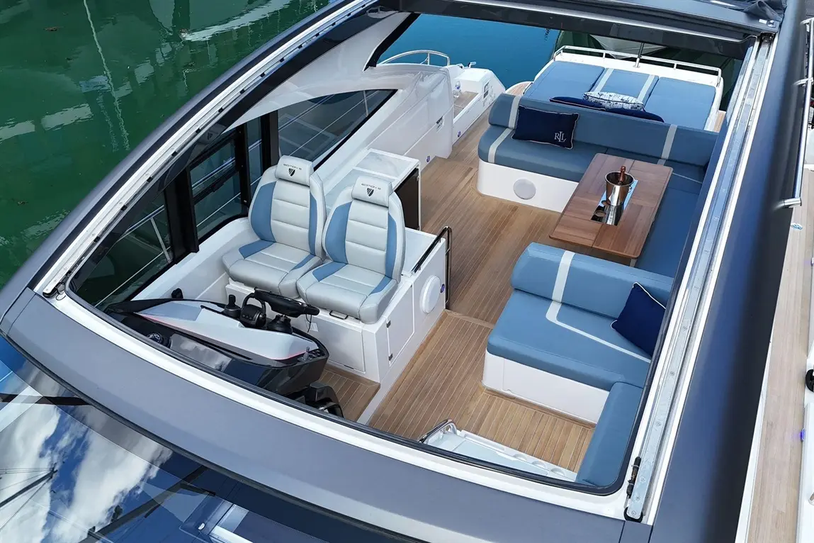 Stylish boat interior featuring ergonomic seating, wooden flooring, and a seating area with a table and champagne cooler.
