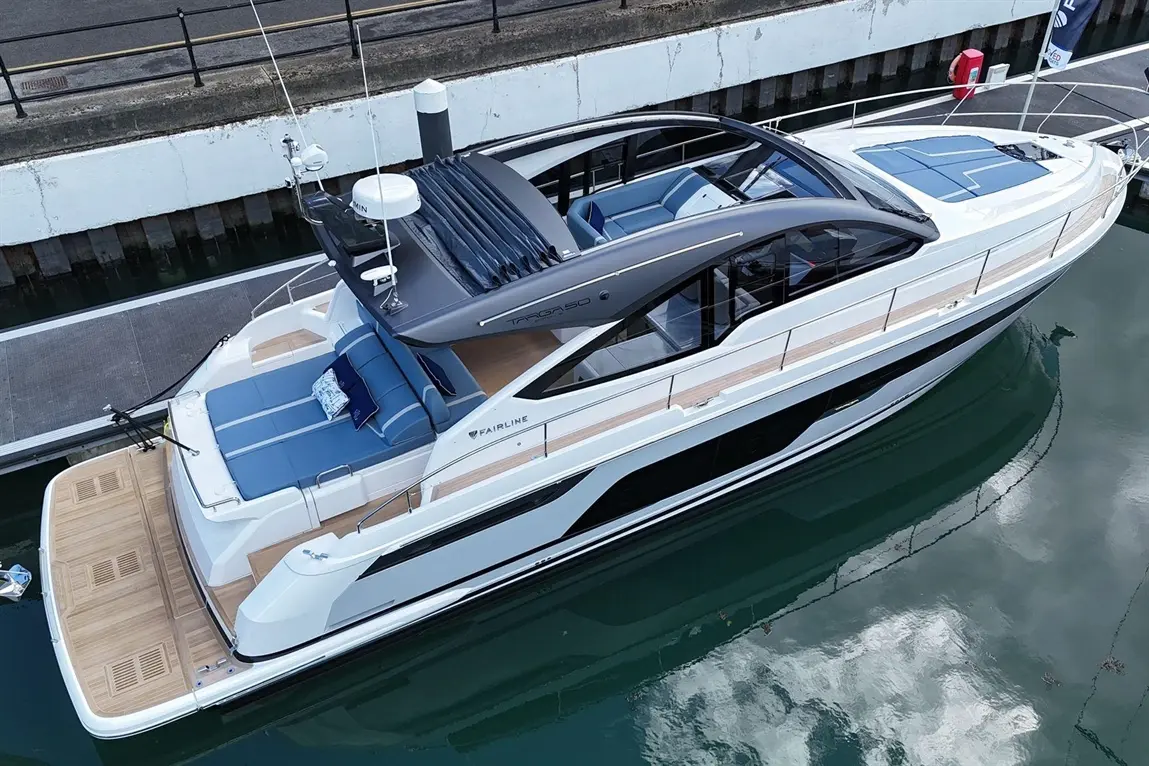 A luxury Fairline Targa 50 yacht docked at a marina, featuring blue upholstery, a sunroof, and sleek modern design elements.