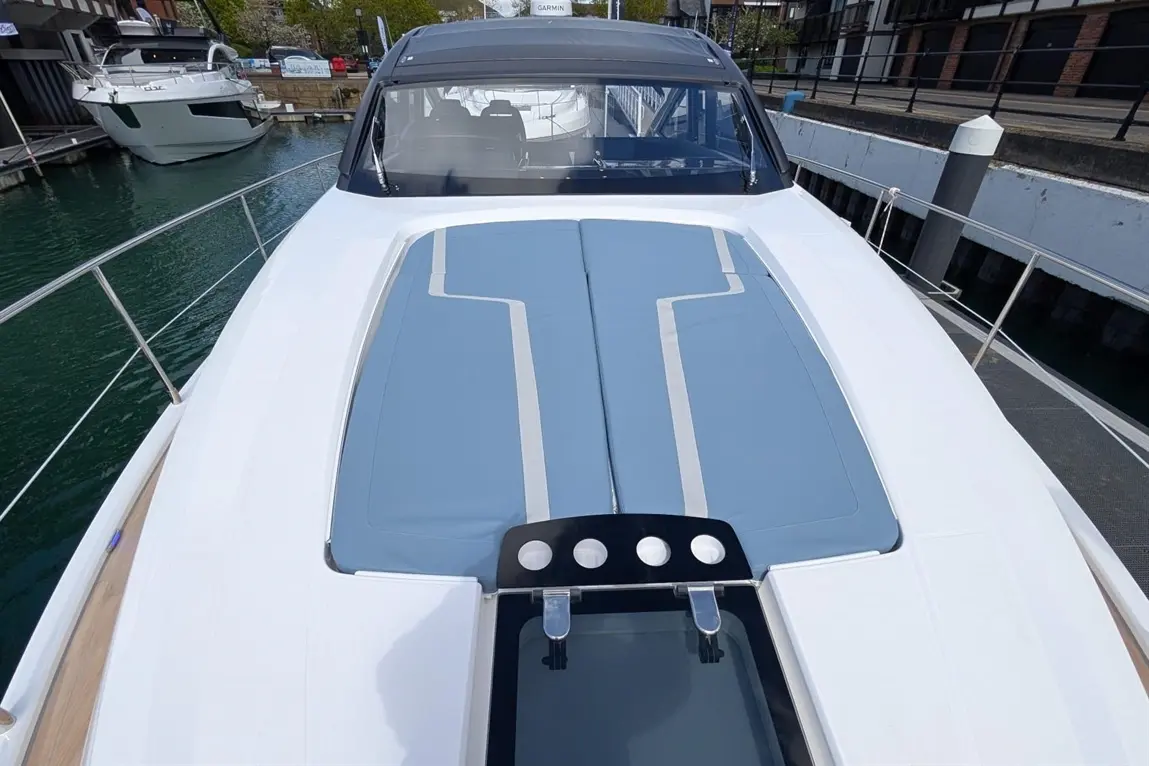 View of a luxury boat's sunbathing area with a blue cover, black control panel, and marina backdrop. Ideal for sailing enthusiasts.
