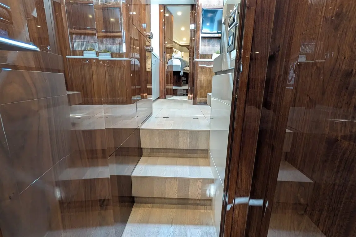 Interior view of a yacht showing polished wooden stairs leading to living spaces, with modern amenities and warm lighting.