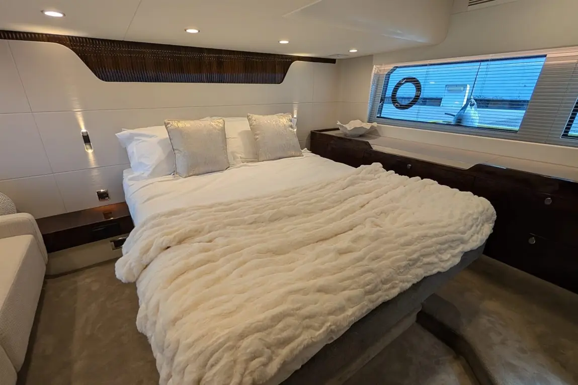 Luxurious cabin with a double bed, plush blanket, silver cushions, and a window offering a view of the outside.