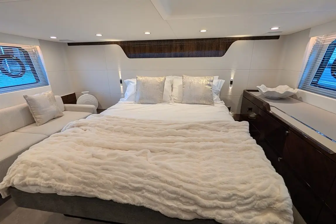 Luxurious bedroom featuring a plush bed with decorative pillows, soft blankets, and a stylish armchair, accented by modern lighting.