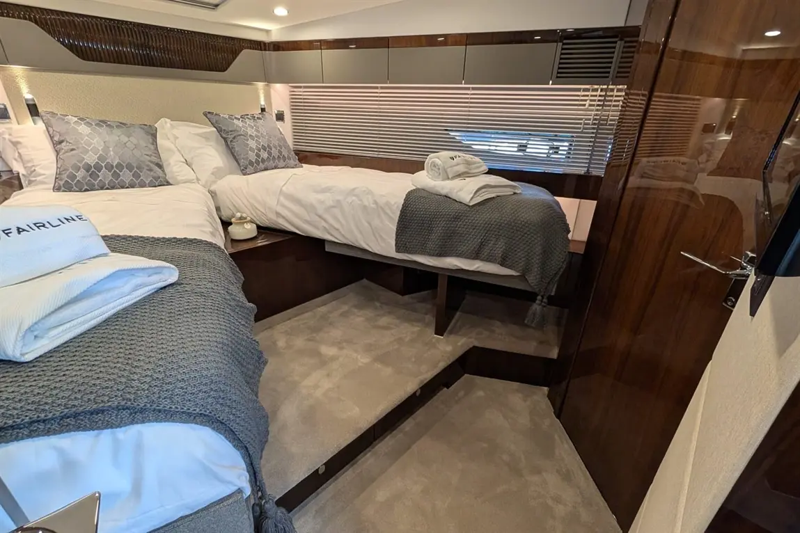 Luxury dual-bed cabin with grey bedding, textured pillows, and a mirror-effect door, showcasing elegant yacht decor.
