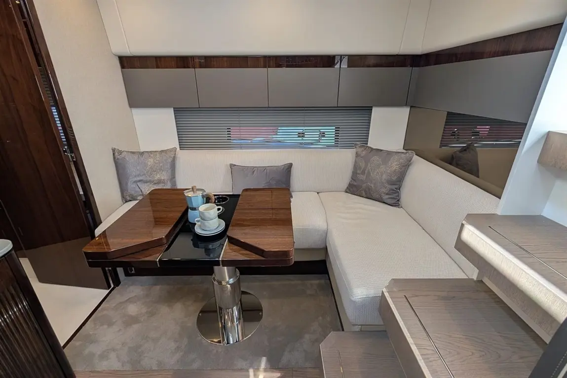 Luxurious yacht interior featuring a cosy lounge with a modern table, cushions, and a coffee set on a plush carpet.