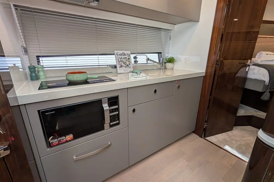 Modern kitchen galley with a microwave, sink, and decorative elements including a plant and a recipe book titled "Galley.