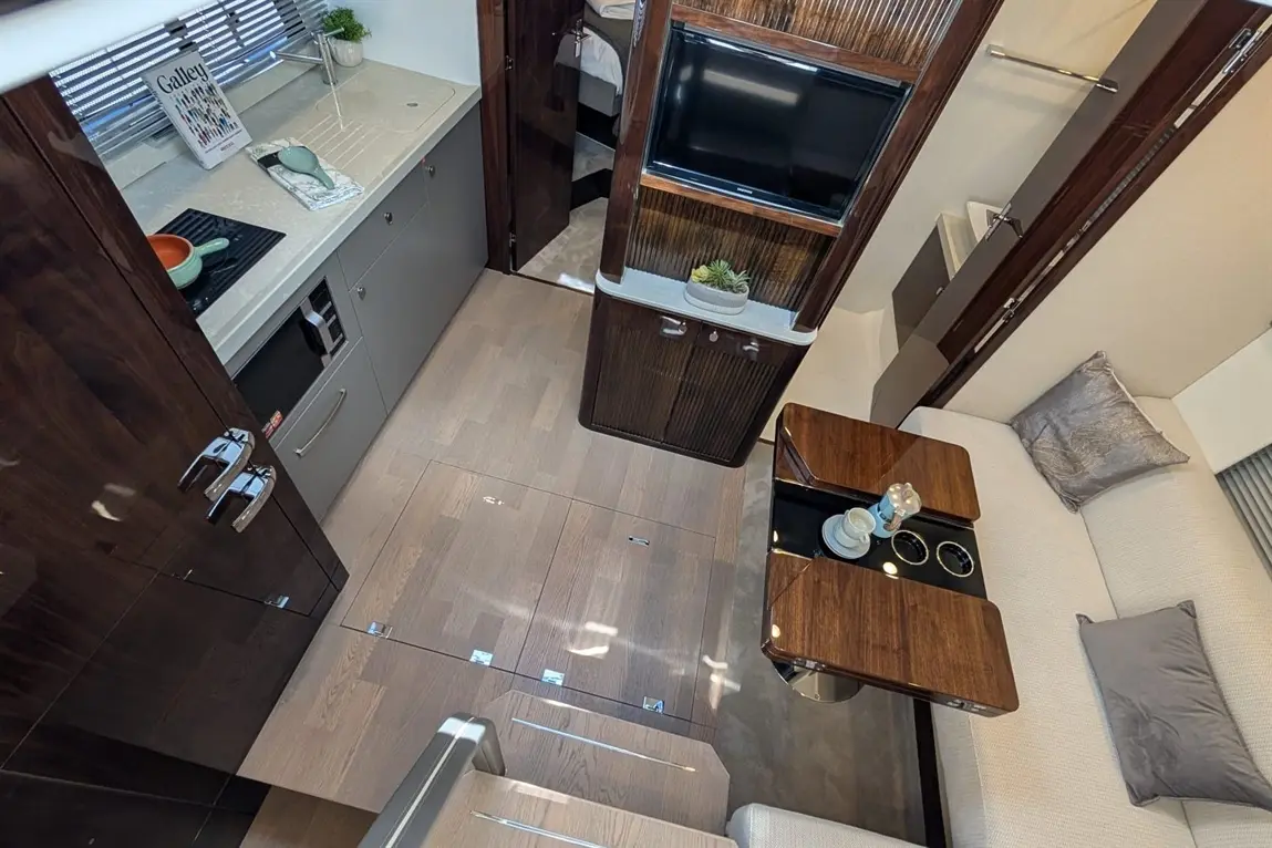 Modern kitchen and lounge area featuring sleek cabinets, a dining table, and plush seating in a stylish interior design.