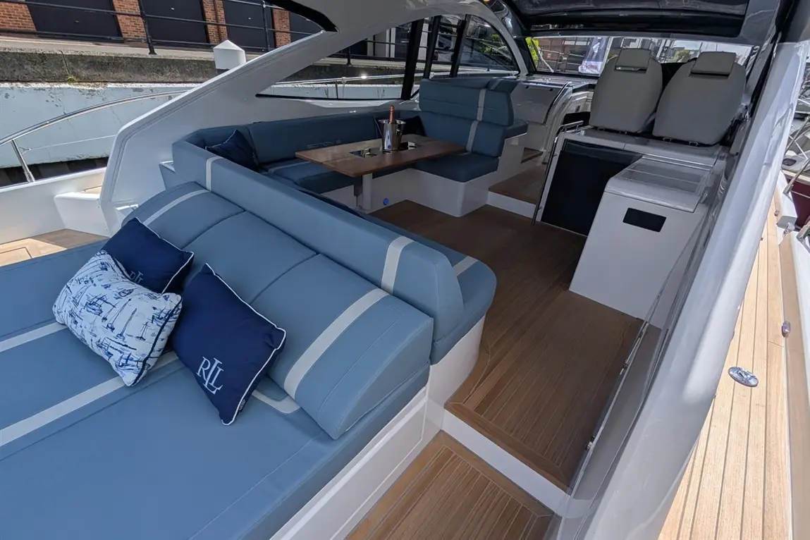 Luxurious yacht interior featuring blue seating, wooden flooring, and a dining table with a champagne bucket. Relaxing atmosphere.