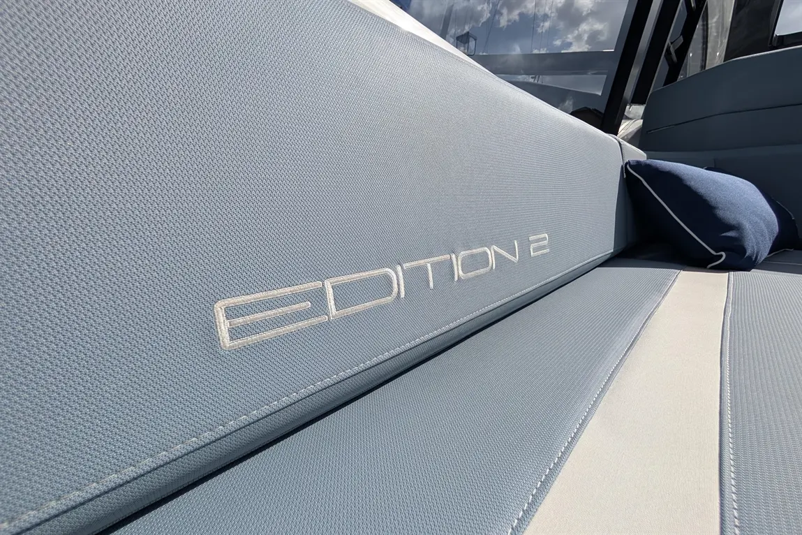 Blue upholstered seating with white stripe and a cushion, featuring the text "EDITION 2" in a sleek font.