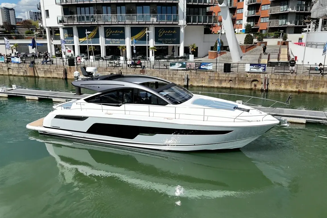 A luxurious white yacht docked at Banana Wharf, reflecting on the calm water, surrounded by waterfront buildings.