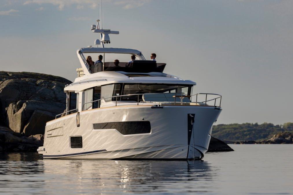 A luxurious yacht anchored on calm waters, with people enjoying time on the deck against a scenic coastal backdrop.