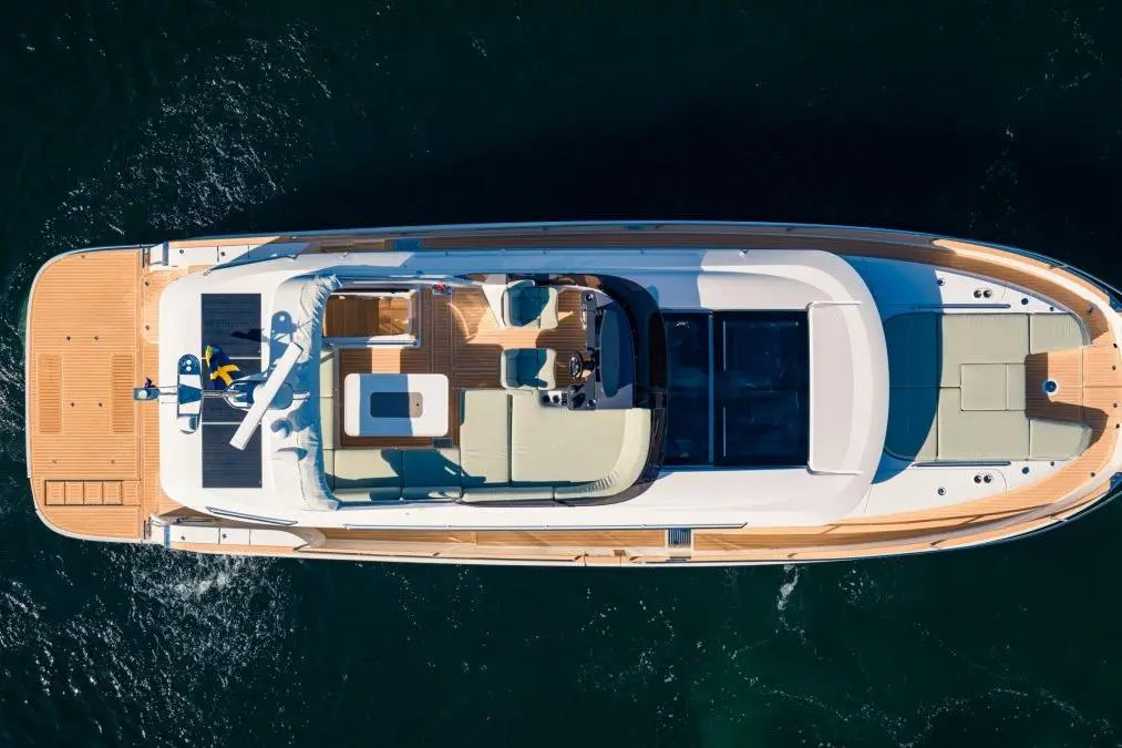 Aerial view of a luxury yacht deck with seating areas, a table, a steering area, and solar panels, surrounded by water.