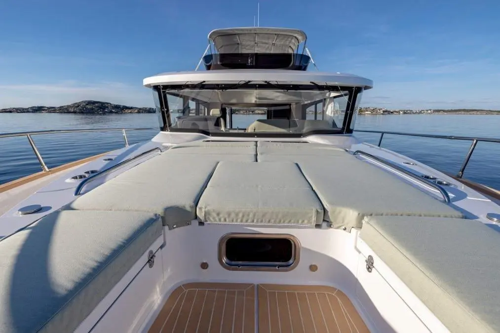 Luxury motorboat deck with plush cushions, overlooking calm waters and distant islands under a clear blue sky.