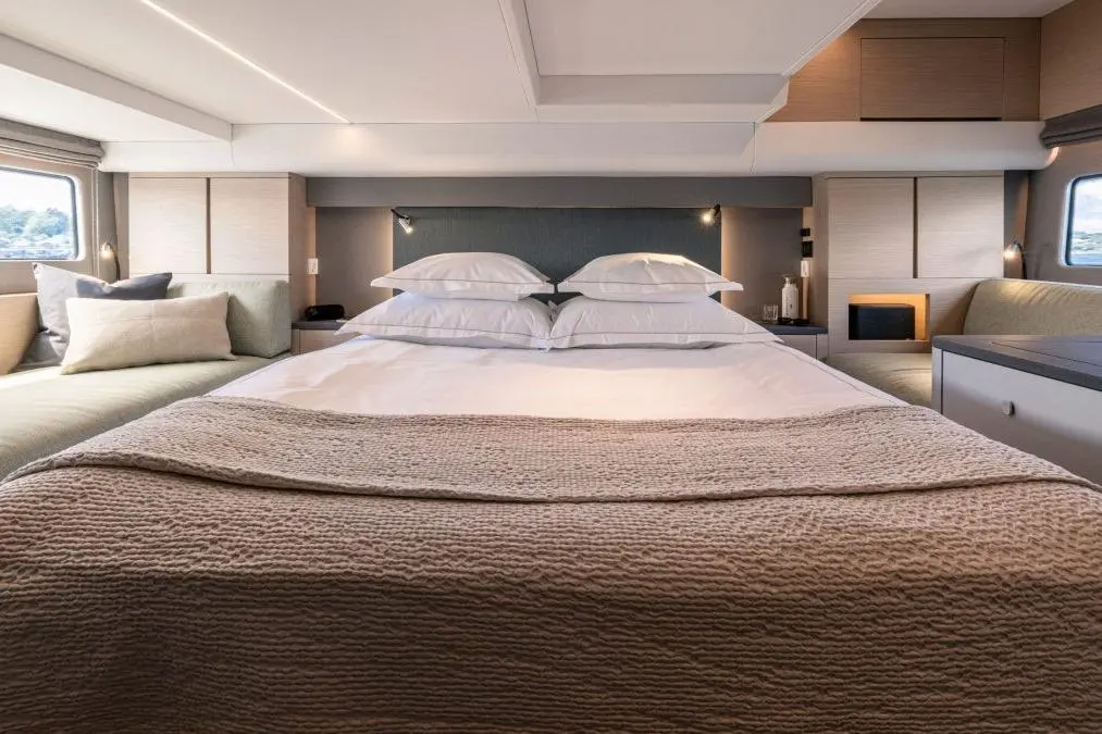 Modern yacht interior featuring a spacious bedroom with a neatly made bed, soft pillows, and stylish furnishings.