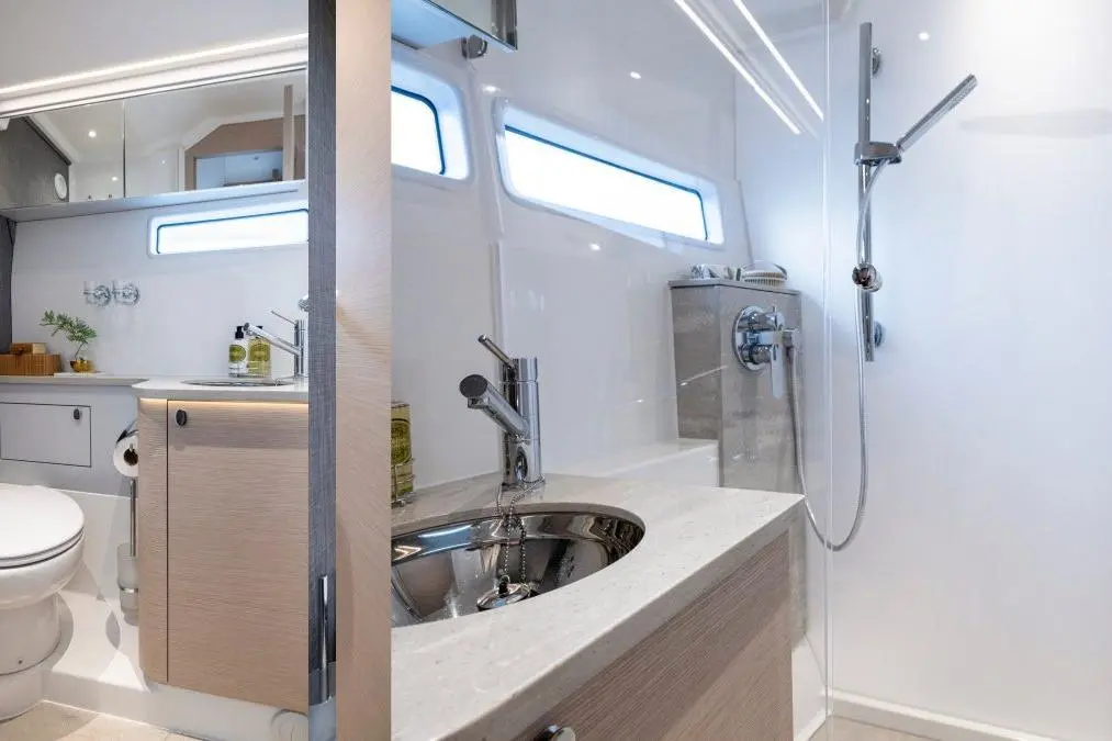 Modern bathroom with a shower, sink with a sleek faucet, and natural light from windows, featuring wooden accents.
