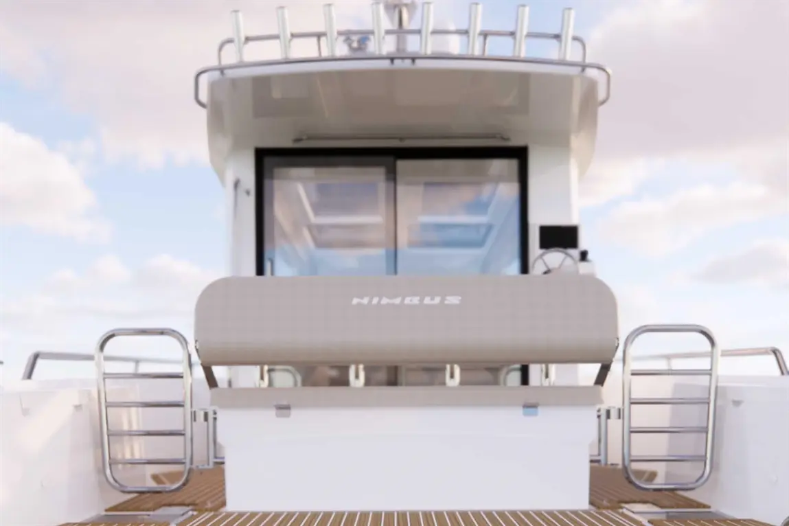 View of a Nimbus boat's deck, featuring a cushioned seating area and a metal ladder against a backdrop of a spacious cabin.