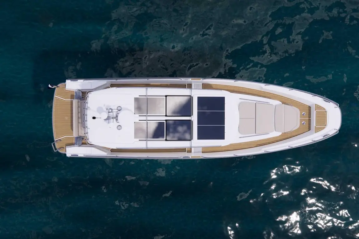 Aerial view of a sleek yacht with solar panels on the deck, floating on clear blue water.