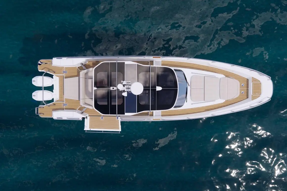 Aerial view of a luxury yacht with a teak deck, sun loungers, and sleek design, set in clear blue waters.