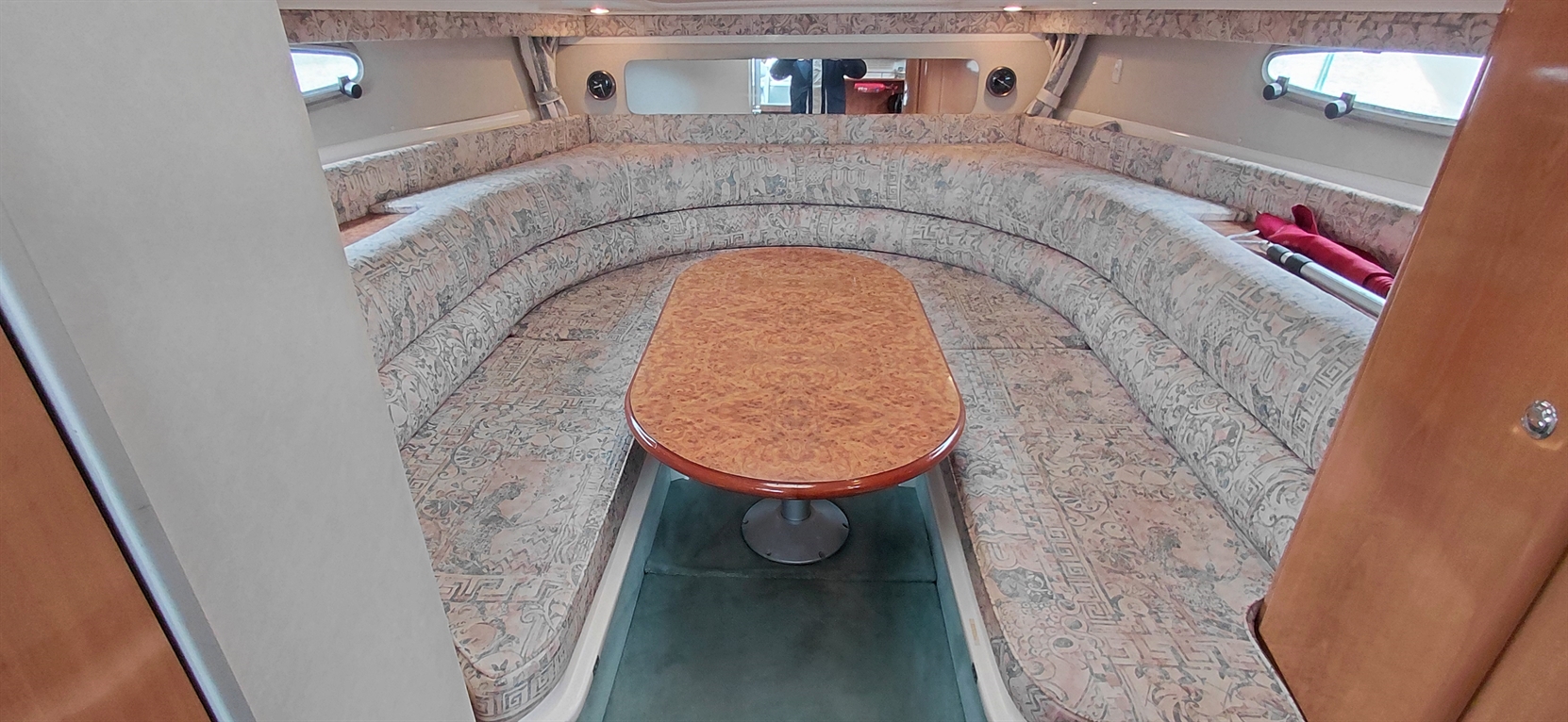 Cozy boat interior featuring round seating with patterned upholstery and a central wooden dining table.