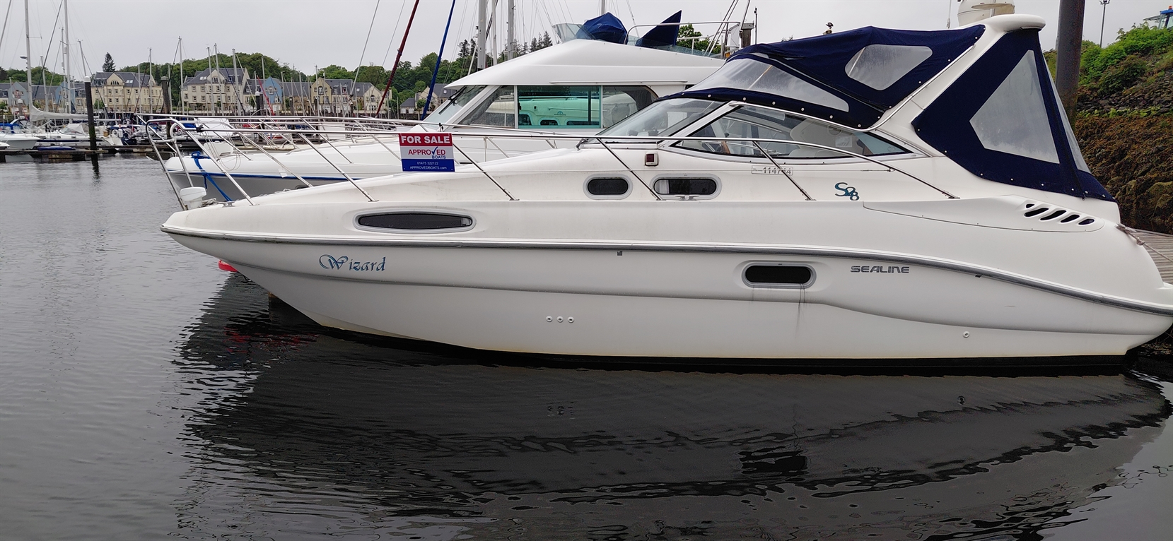 White Sealine S8 boat named "Wizard" docked in marina, with a "For Sale" sign prominently displayed.