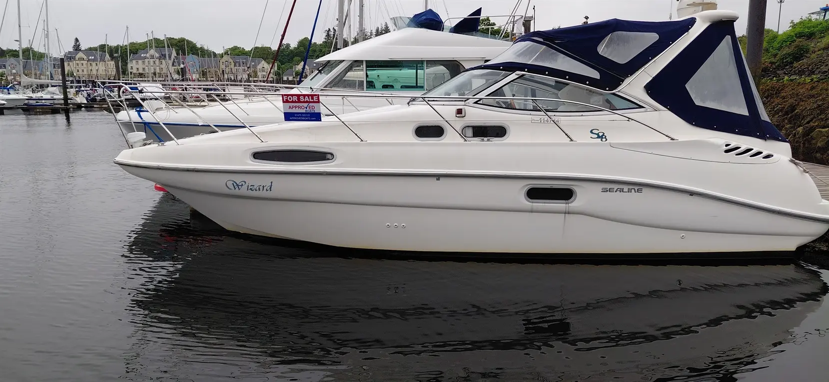 White Sealine S8 boat named "Wizard" docked in marina, with a "For Sale" sign prominently displayed.