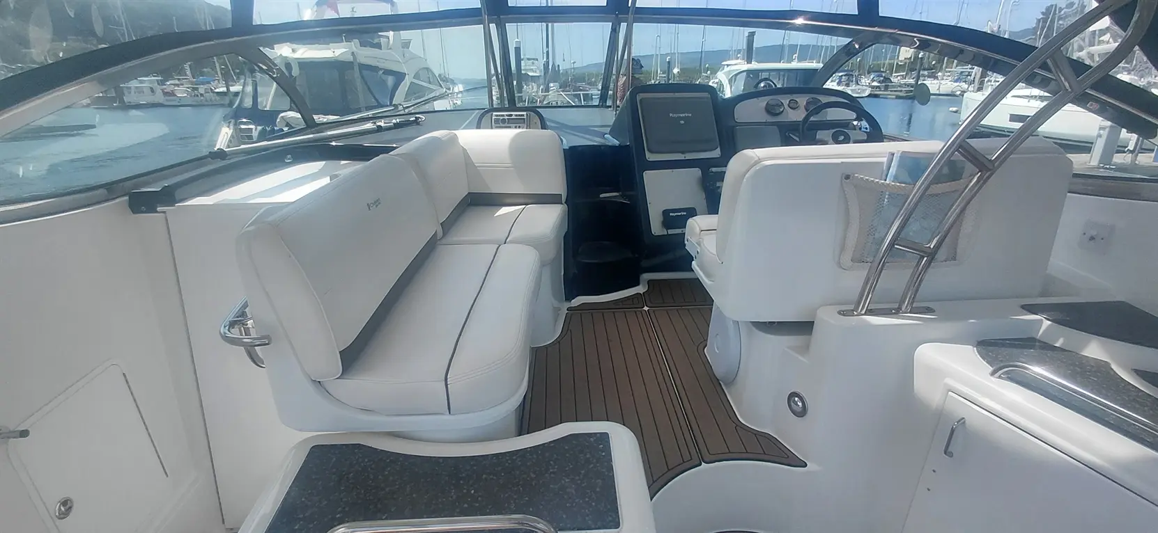 Interior view of a sleek, modern boat cockpit featuring white leather seating, a steering wheel, and a navigation display.