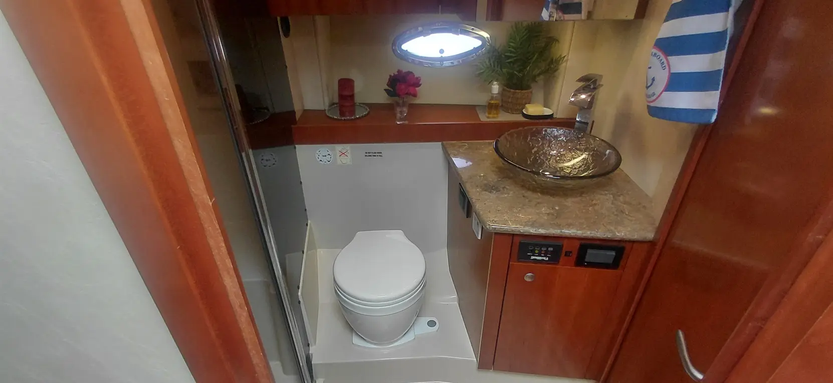 Compact bathroom featuring a toilet, vessel sink, granite countertop, and decorative items like flowers.