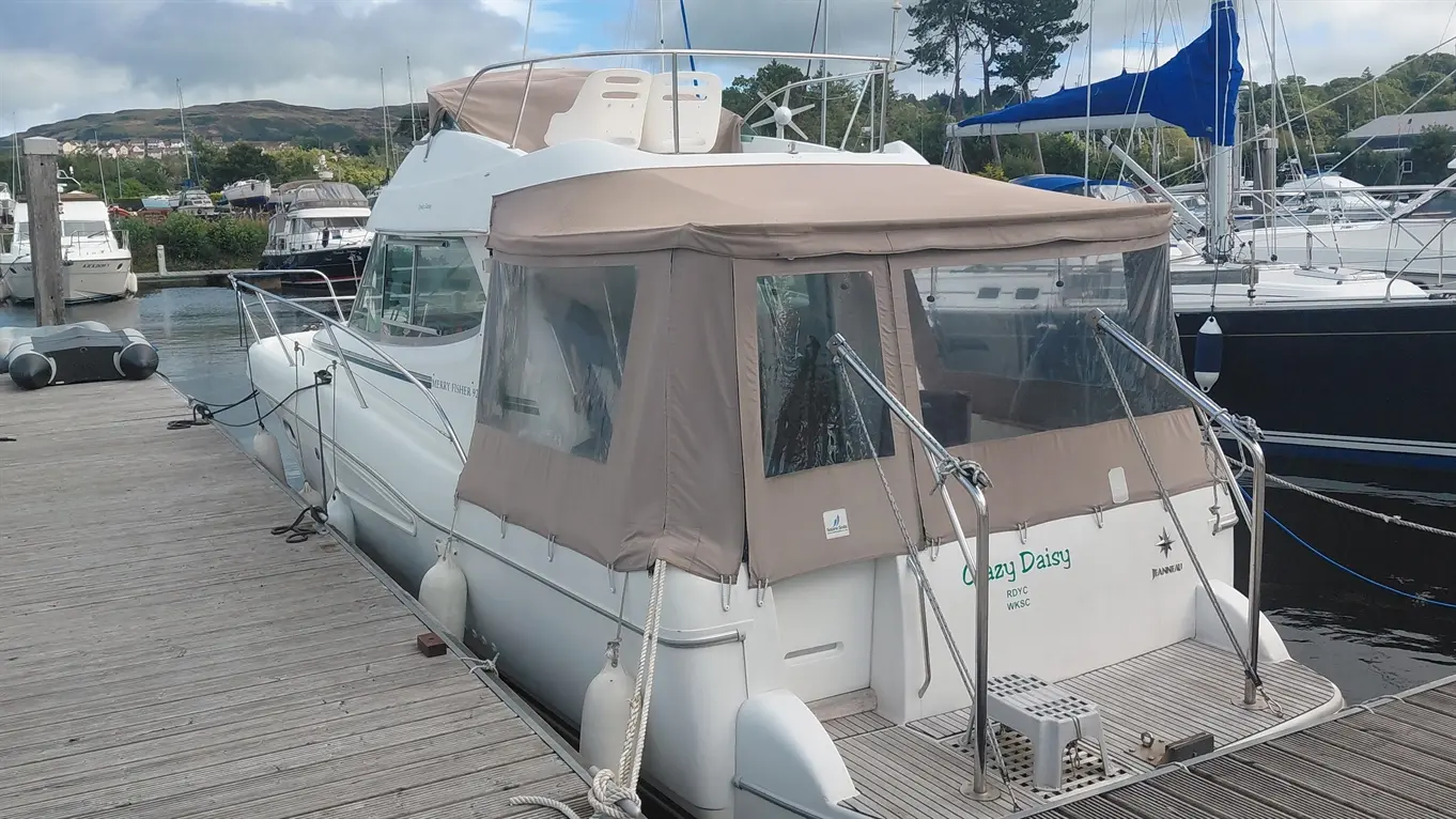 Jeanneau Merry Fisher 925 motorboat moored at a marina, with a beige canopy and nearby yachts.