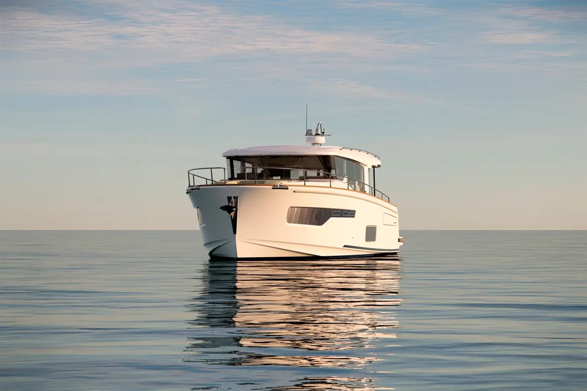 A sleek white yacht floats on calm waters, reflecting the serene sky, showcasing modern design and tranquil surroundings.