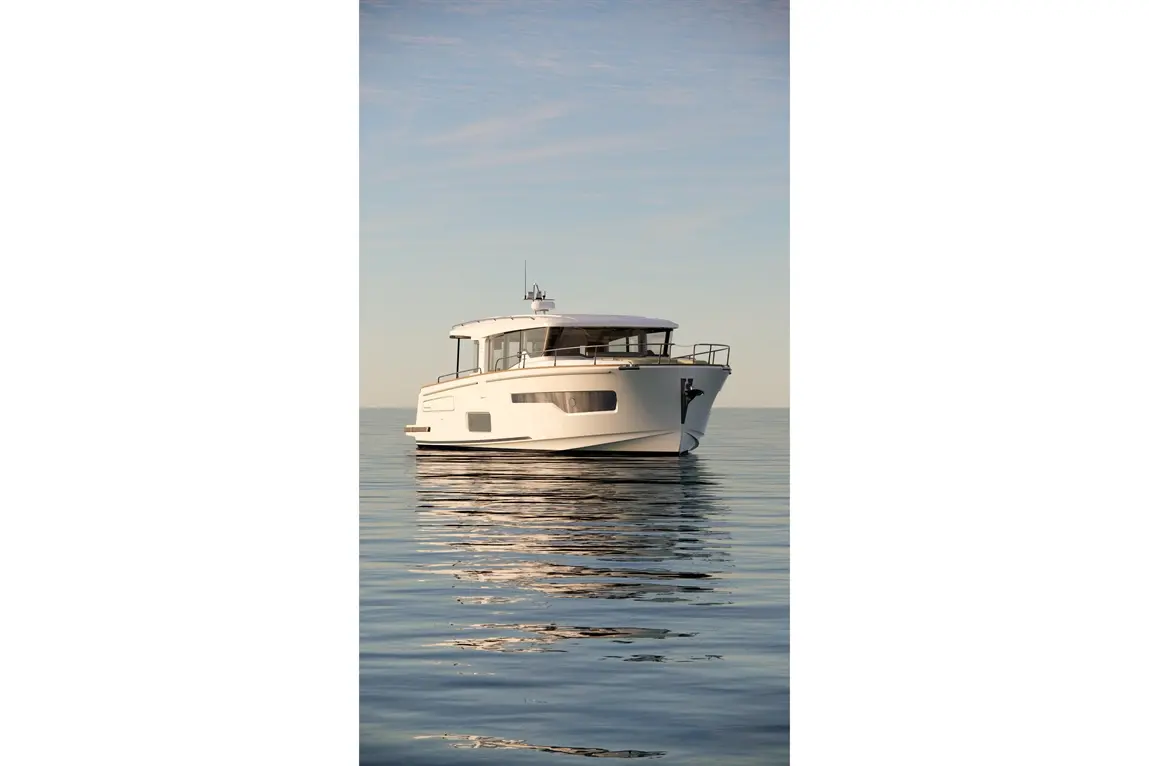 A sleek white motorboat floats on calm water under a clear sky, reflecting light gently off its surface.