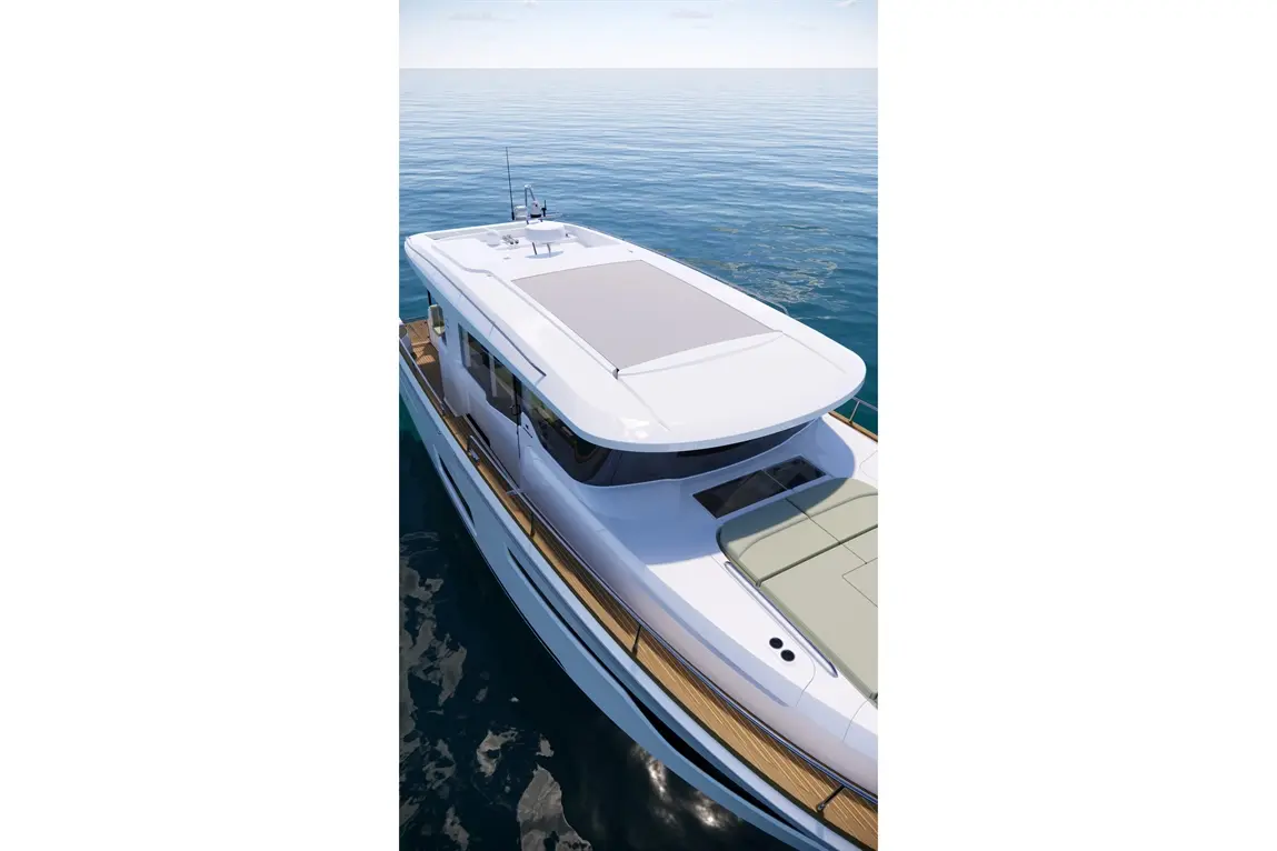 Aerial view of a white motor yacht with a spacious deck, blue ocean water, and a clear sky with a few clouds.