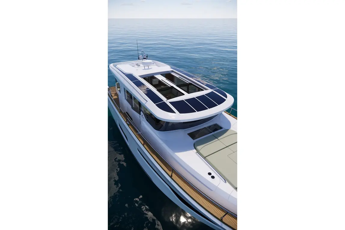 Aerial view of a modern boat with solar panels on the roof, anchored in calm waters under a clear sky.