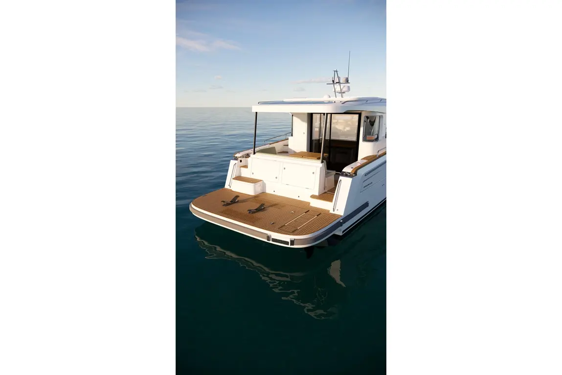 A white boat with a wooden deck is anchored on calm water, reflecting a clear sky with few clouds.