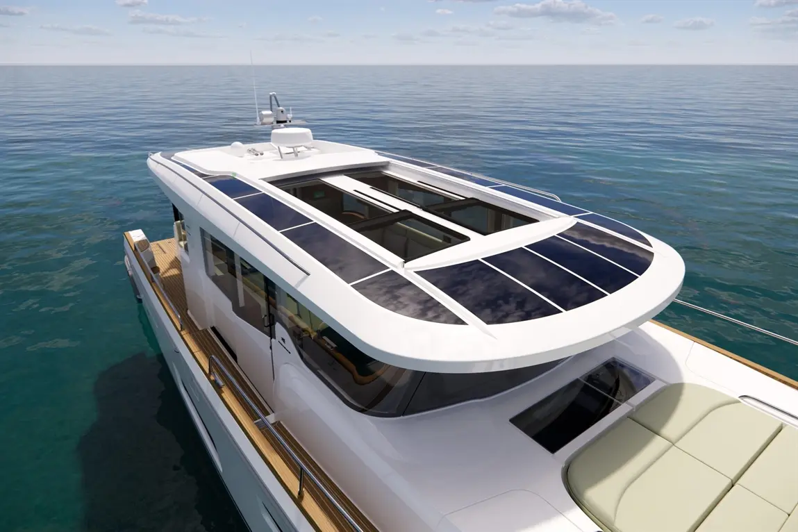 Modern yacht with solar panels on the roof, viewed from above, surrounded by calm blue waters and a clear sky.