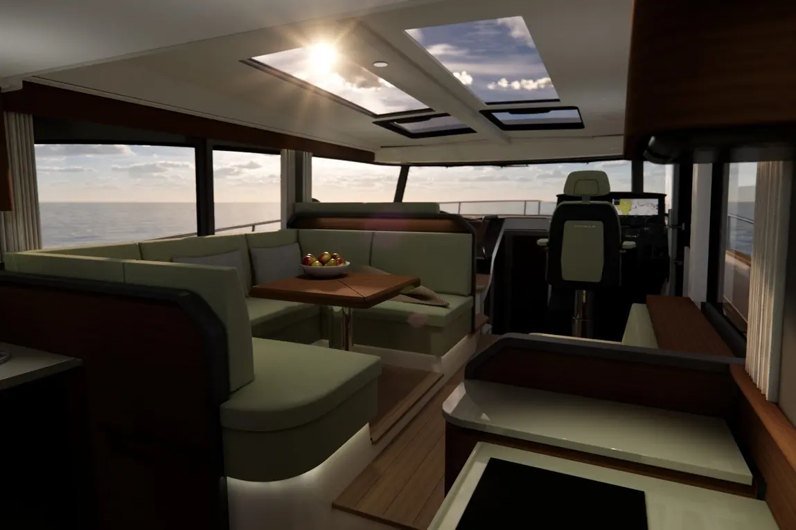 Interior of a modern yacht featuring a dining area with green seating and a table with a bowl of fruit, overlooking the sea.
