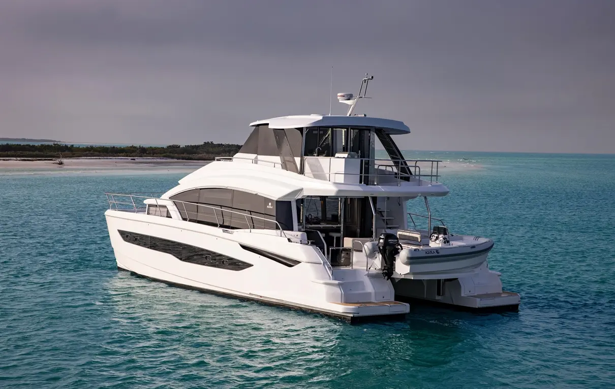 Luxury motor yacht anchored in turquoise waters, featuring a sleek design and a small tender boat alongside.