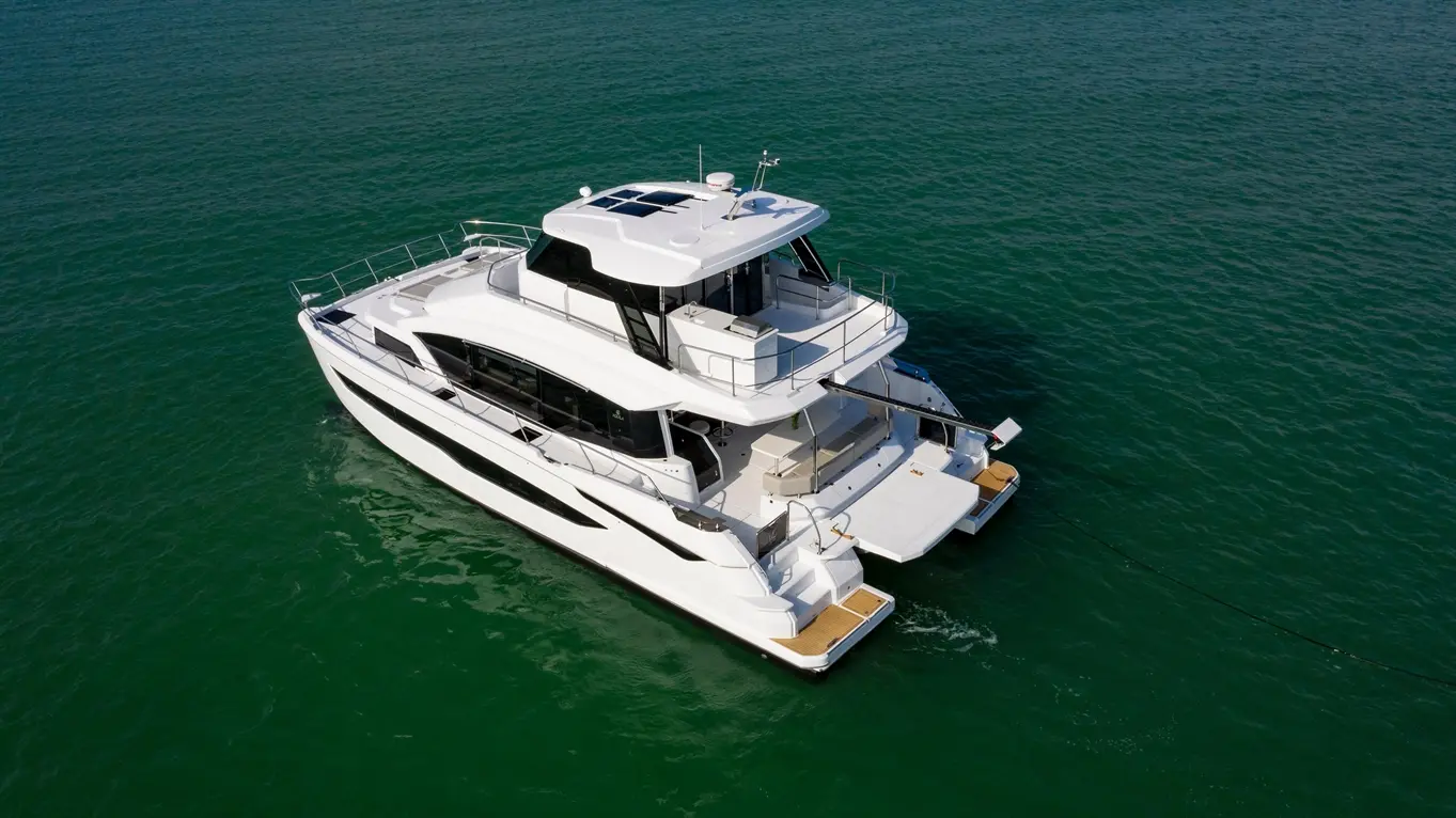 Luxury motor yacht anchored in calm green waters, showcasing modern design features and spacious outdoor areas.