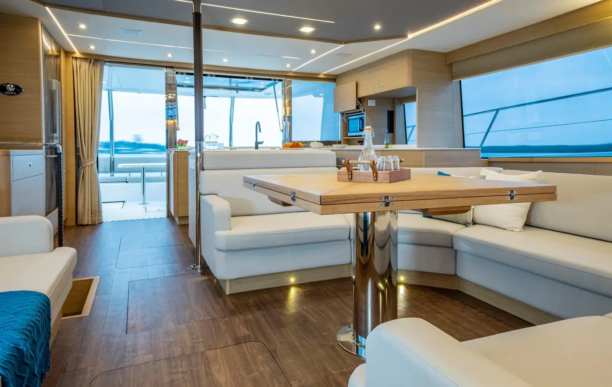 Luxurious yacht interior featuring a modern seating area, dining table, and large windows with ocean views.