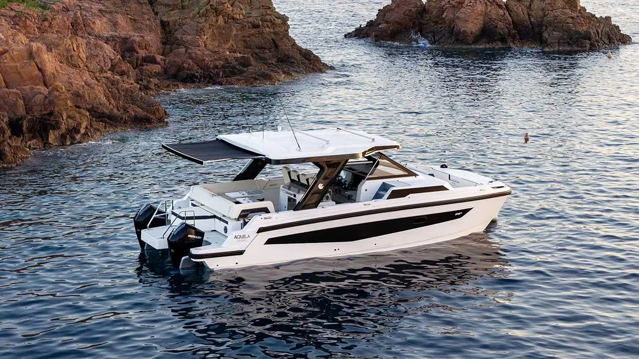 Aquila 35 Sport motorboat anchored in a rocky coastal cove, viewed from the side.